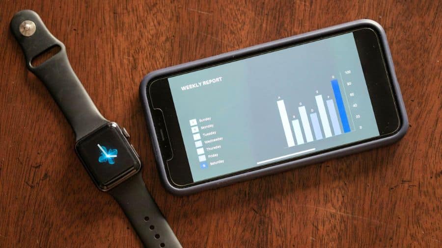 smartwatch preto conectado com um celular que está mostrando dados