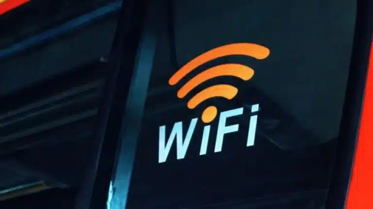 Ícone de Wi-Fi laranja e branco colado na janela de um ônibus vermelho, indicando disponibilidade de internet sem fio