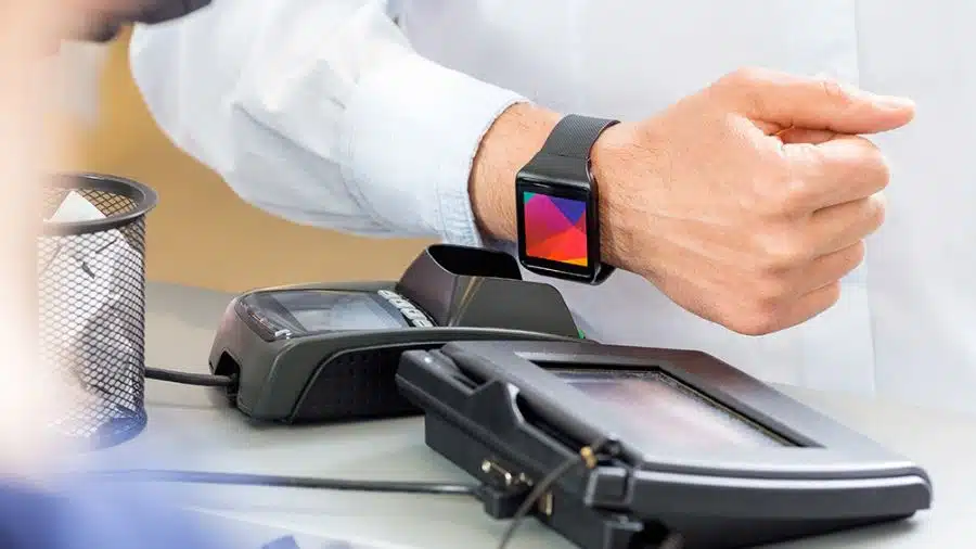 Pessoa realizando pagamento por aproximação com smartwatch em maquininha de cartão
