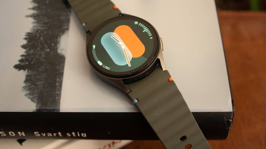 Galaxy Watch 7 com mostrador colorido apoiado sobre a caixa do produto, destacando o design da tela e da pulseira