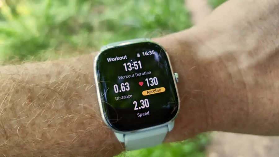 Smartwatch Amazfit GTS 4 Mini no pulso exibindo dados de treino com distância, batimentos e velocidade